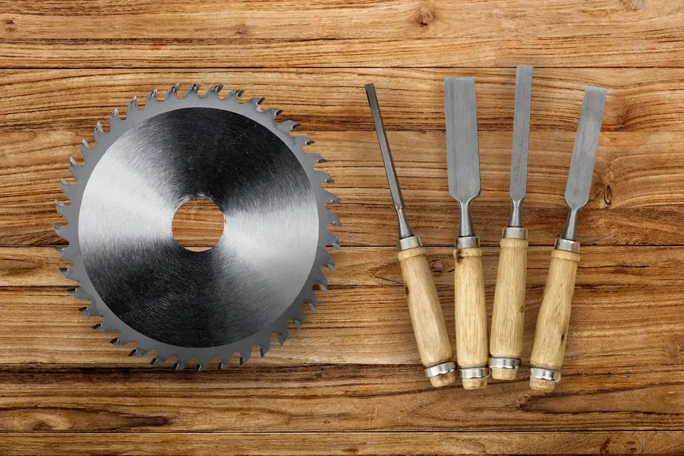 Lame de scie circulaire et ciseaux à bois présentés sur un plan de travail